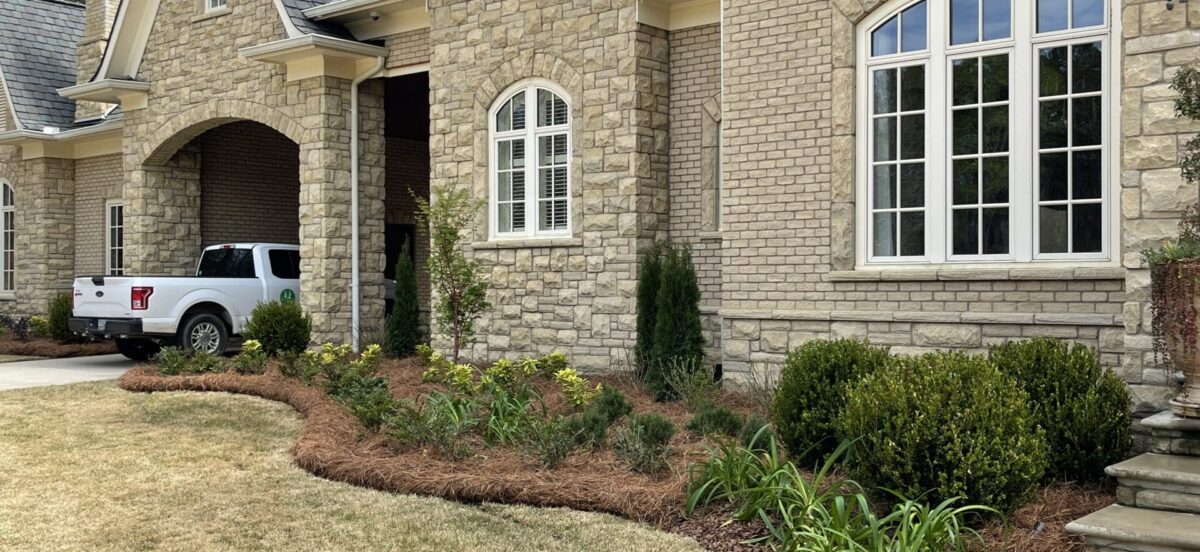 well-maintained flowerbed with pine straw