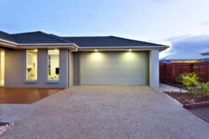 Part of this luxurious house includes a garage with a white door and illuminated by two small lights under the ceiling.