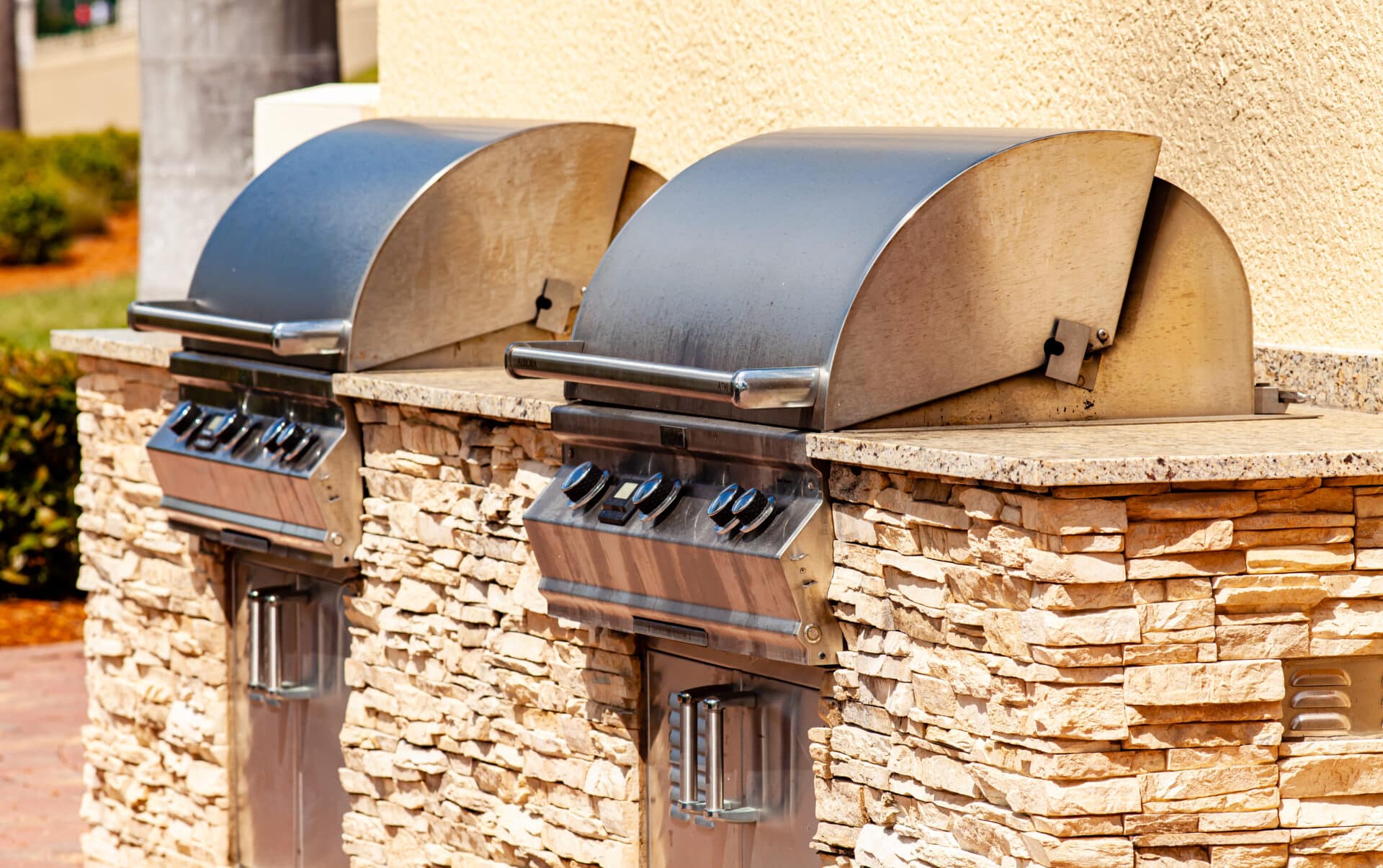 An outdoor kitchen with two grills mounted in a stone counter.